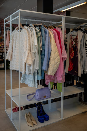 womens summer clothing in various colors and fabrics hanging on hangers in thrift shop. Second handの写真素材