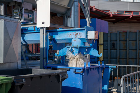 Industrial machine filling plastic bag in blue container outdoors at recycling plantの写真素材
