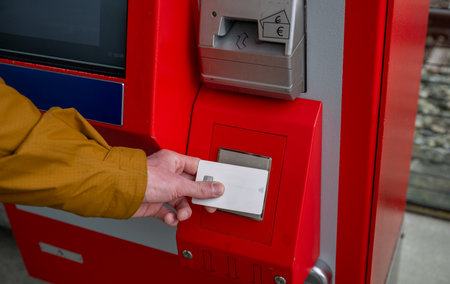 Person using contactless card at red ticket vending machine on train platformの写真素材