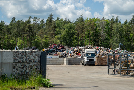 Industrial waste and scrap metal recycling yard in forested area on sunny dayの写真素材