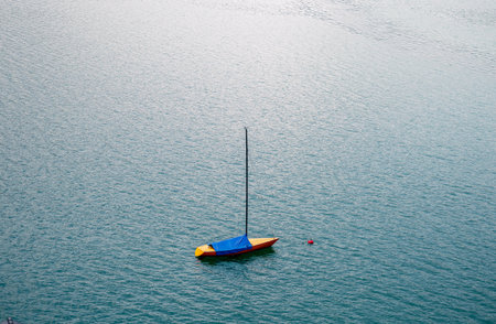Yellow sailboat with blue cover floating on alpine lake in the Austrian Alpsの写真素材