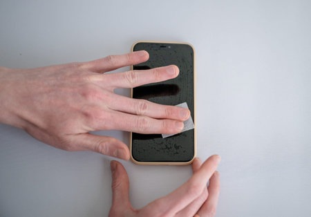 Man cleaning smartphone screen with dry wipe before applying screen protector