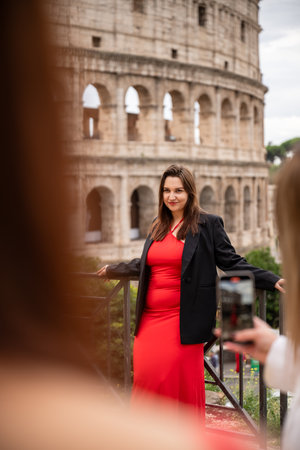 Woman in red dress and black blazer posing near Colosseum in Romeの写真素材