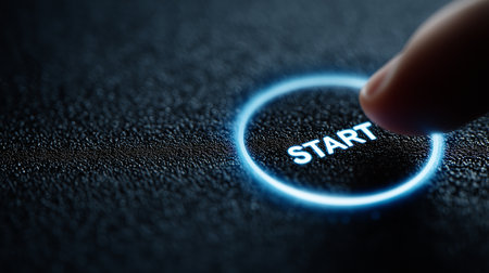 Finger pressing glowing start button in dark futuristic interfaceの素材