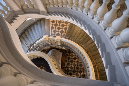 Elegant spiral staircase with geometric tiled floor and classic balustrade