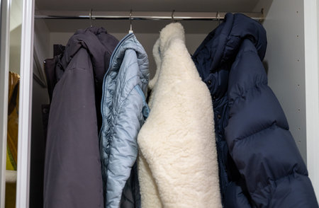 Warm winter jackets hanging in wardrobe showing cozy seasonal clothing storage