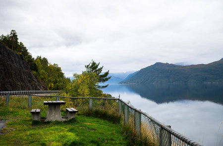 Scenic lakeside picnic area with mountain reflection in calm Norway fjord