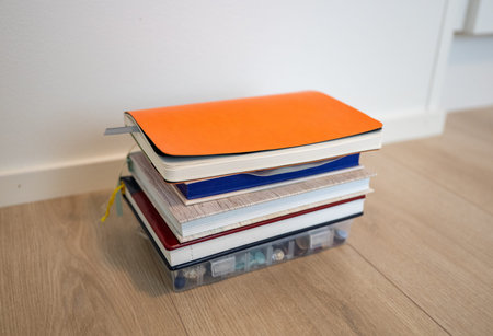 Stack of notebooks and planners on floor in minimalist home interior