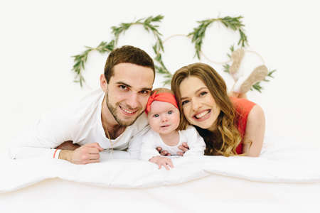 Beautiful caucasian family of three sitting on a bedの写真素材