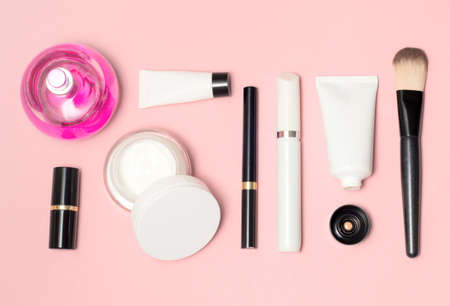 Concept of a white and black cosmetic supplies top view on pink background. Lipstick, eyeliner, brush, parfumeの写真素材