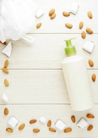 Composition with plastic bottle and mesh shower sponge for body care and beauty products. Beautiful background with almond and coconut.の写真素材