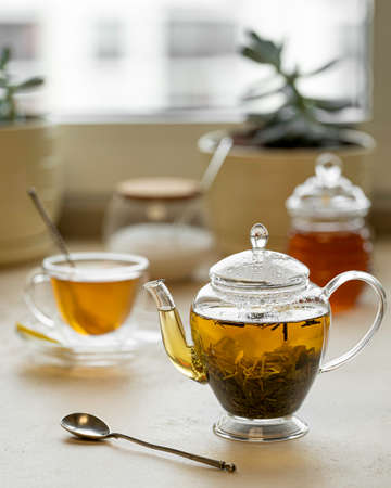tea in a transparent glass teapot and cup on a light backgroundの写真素材