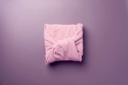 cute beautiful pink gift wrapped in cotton, on a lilac background close-up view from aboveの写真素材