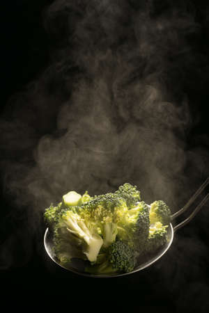 hot boiled steaming broccoli close-up on a dark background,vertical image. High quality photoの写真素材