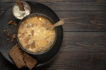 mushroom soup with sour cream and bread in a black dish in rustic style top view. High quality photo