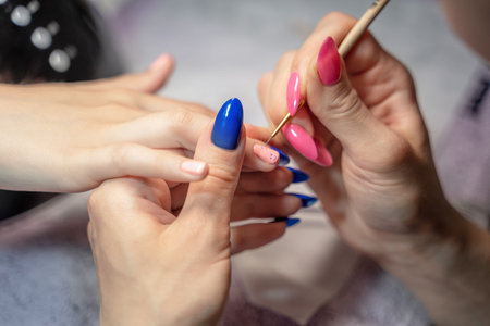 the manicure process of a teenage girl in close-up, the master draws smiles on the nail