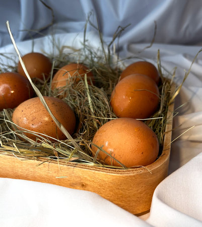 Eggs in a wooden basket placed in a dry straw pile.