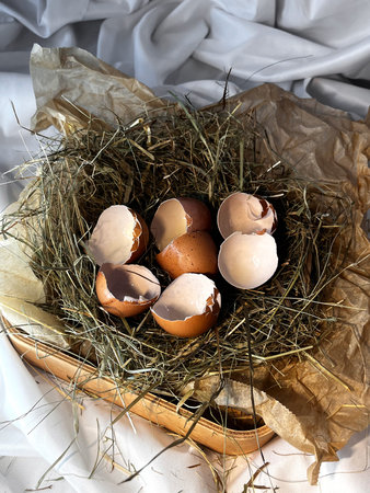 Eggshell in a wooden basket placed in a dry straw pile.