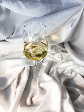 White wine chardonnay sauvignon blanc glass on a white textile background. Top view.の写真素材