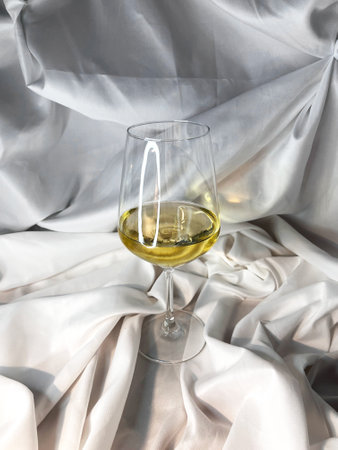 White wine chardonnay sauvignon blanc glass on a white textile background. Top view.の写真素材