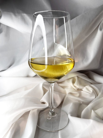 White wine chardonnay sauvignon blanc glass on a white textile background. Top view.