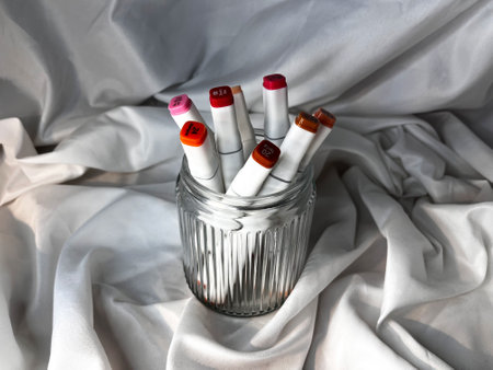 Group of White markers of different colors in a glass on white textile backgroundの写真素材
