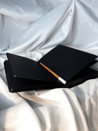 Black leather notebook or sketchbook with black pages on white textile background.