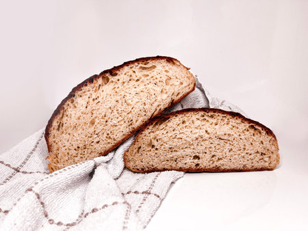 Freshly baked round bread cut into slices on a white background. Close up.