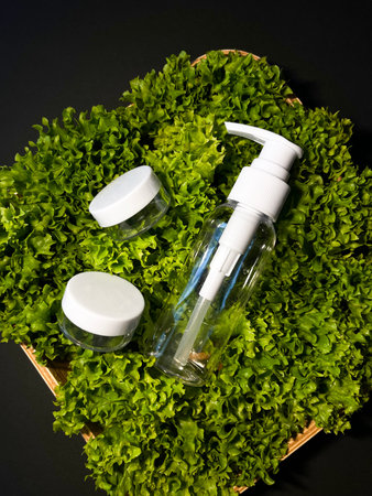 Various cosmetic product containers and bottles on green in wooden box on black background, copy...