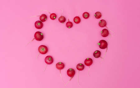 Red radish shaped like a heart on a pink background.の写真素材
