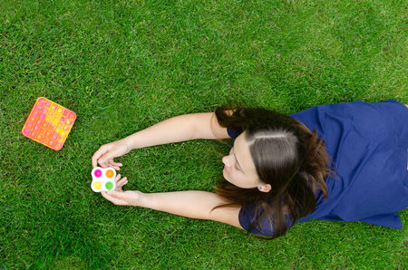 A teenage girl is playing with simple dimple and popit anti stress toys outside on the lawn.
