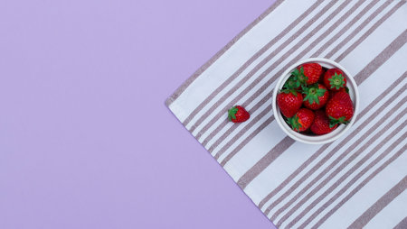 A top view of a bowl with strawberries on a kitchen towel. Raw summer food concept.の写真素材