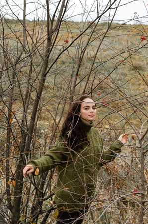 Dreamy brunette young woman stands in the forest surrounded by tree brunches. One with nature...
