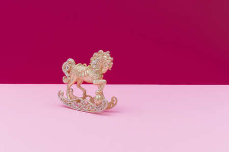 Golden and silver Christmas toy horse decoration on a pastel pink and dark mauve background. Copy space.の写真素材
