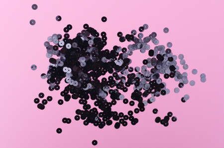 Top view of black decorative sparkling sequins on pastel pink background. Copy space.の写真素材