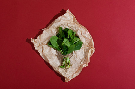 Green spinach vegetables on a craft paper and red background.