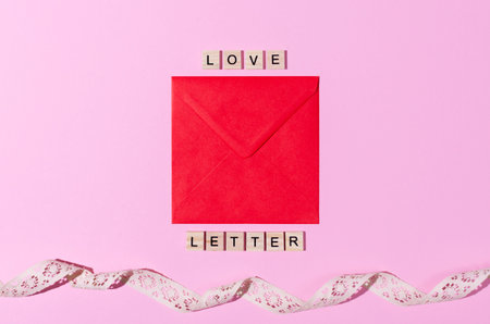 Red envelope on pink copy space background, wooden words love letter. St Valentine, message, proposal, romance concept.の写真素材