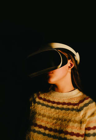 Futuristic shot of a woman in VR goggles standing in the pocket of bright sunset light. High contrast, harsh light shot.の写真素材