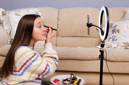 Young caucasian teenage girl recording live-streaming beauty make-up tutorial video for social media...