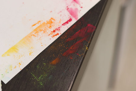 A smeared table with colored soft pastel crayons. Multicolored artists background.