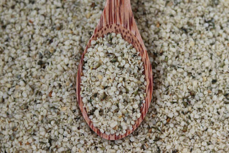 Healthy organic shelled hemp seeds in a wooden spoon close-up.の写真素材