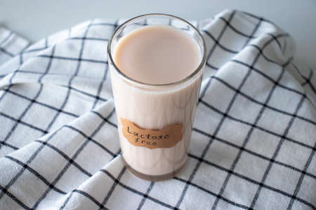 A glass of herbal milk on a napkin with a Lactose Free sign on itの写真素材