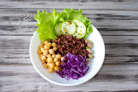Buddha bowl with vegetables, chickpeas, red cabbage, lettuce, red rice, zucchinipi, stachios on...
