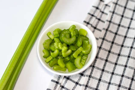 Celery slices in a small white bowl on a white plate with a napkin. Top viewの写真素材