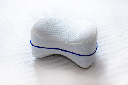 Orthopedic knee pillow for comfortable sleep. The pillow lies on the bed.の写真素材