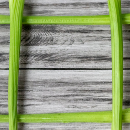 Chefs frame with stalks of green celery on a wooden background. Organic raw ingredients for salad. flat lay. Space for textの写真素材