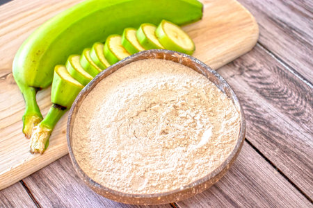 Banana flour in a coconut bowl on a wooden background with fresh bananas. Vivid photoの写真素材