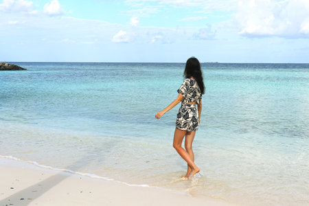 Maafushi, MALDIVES, AUGUST 23 20222, Beach fashion for women. A tall beautiful girl walks along the ocean in the Maldives in a beige linen suit with a tropical pattern.,Illustrative Editorialのeditorial素材
