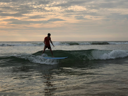 Surfer on the wave. Beginner surfer learned how to ride a board. Waves on the island of Phuket Thailand. Surfer catching a wave at sunsetの写真素材