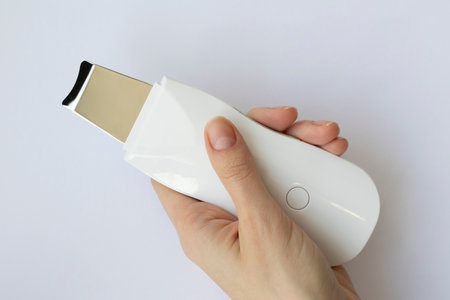 Ultrasonic Skin Scrubber Exfoliating Wand on white background in a woman's hand.の写真素材